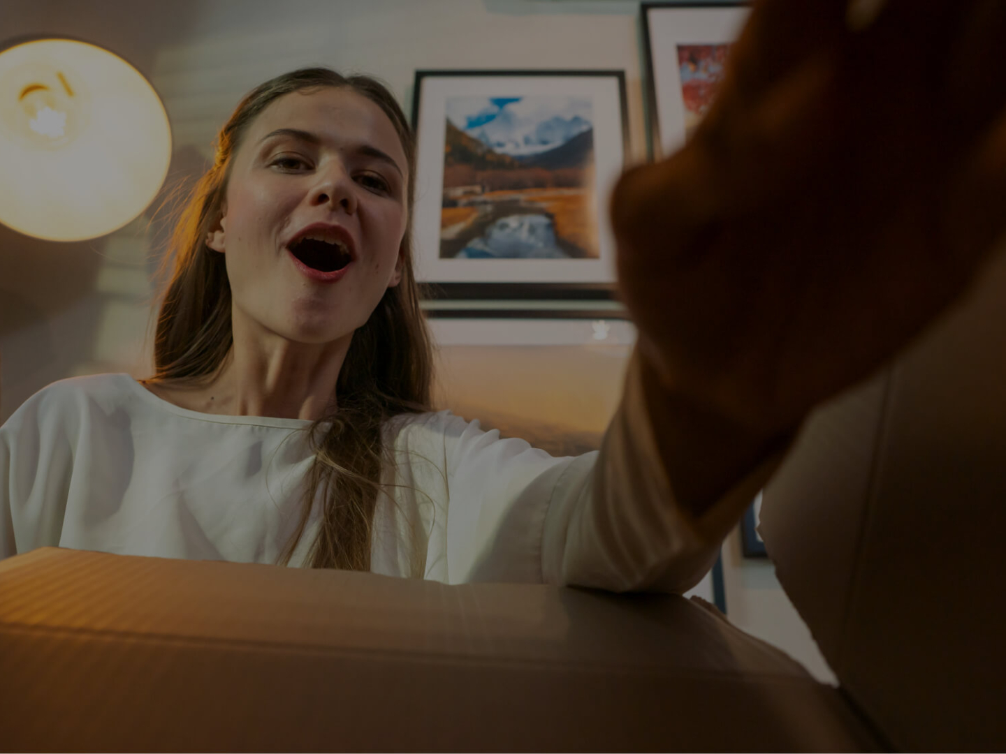 Muchacha asombrada abriendo una caja de su compra de cyber days