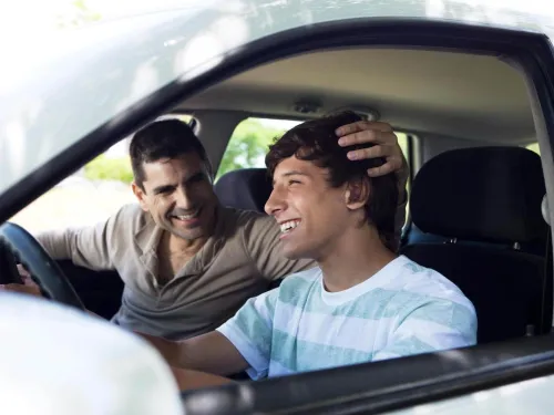 Un padre y un hijo dentro de un vehículo sonriendo 