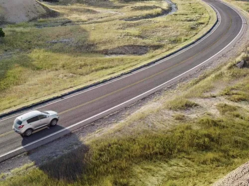 Tarjeta corporativa Gas Club Assist: Un auto circulando por una carretera rodeado de un paisaje de montañas