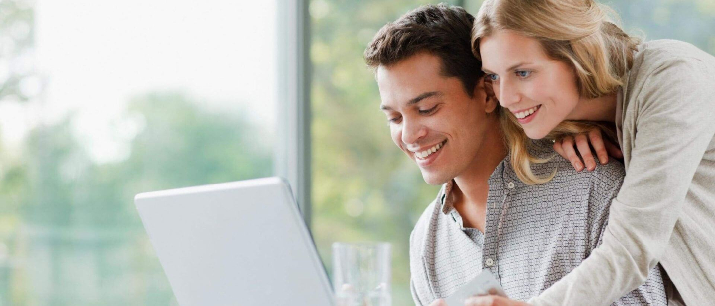 Botón de pagos Diners Club: Una pareja sonriendo frente a una computadora