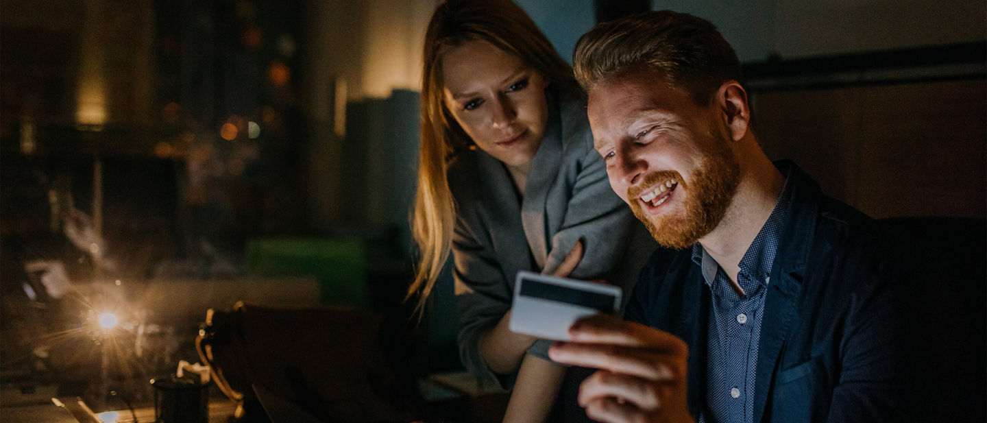 Dos personas sonriendo con una tarjeta de crédito