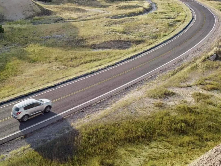 Tarjeta corporativa Gas Club Assist: Un auto circulando por una carretera rodeado de un paisaje de montañas