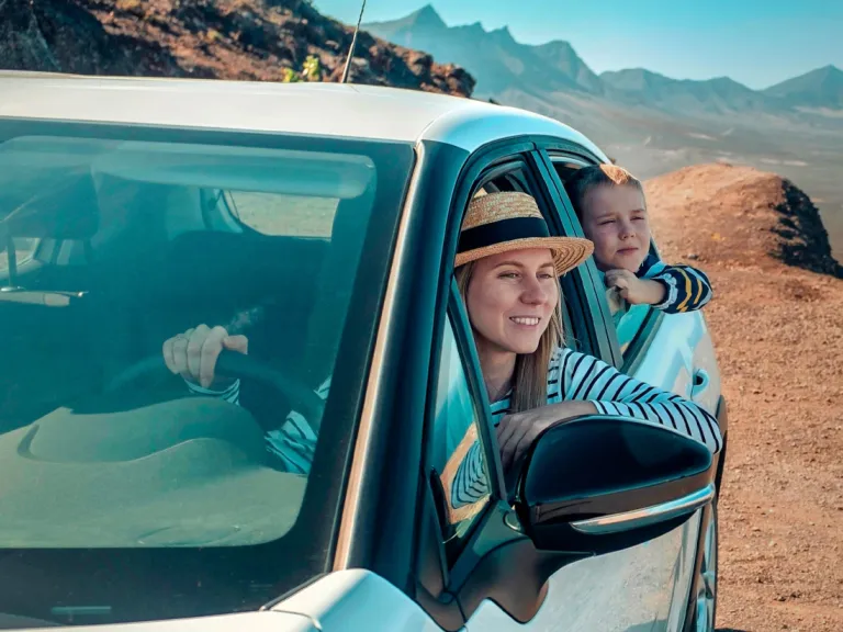 Gente sonriendo en un carro por la costa