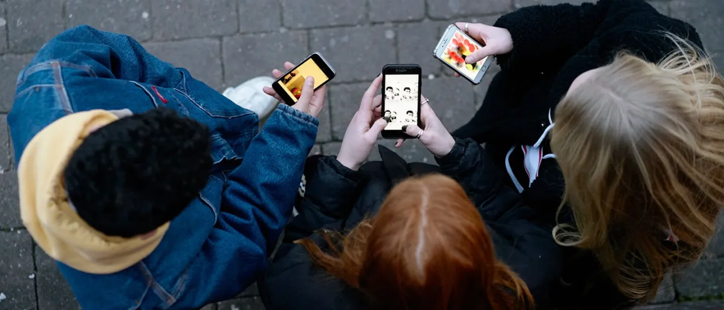 Vista superior de tres personas mirando sus celulares 