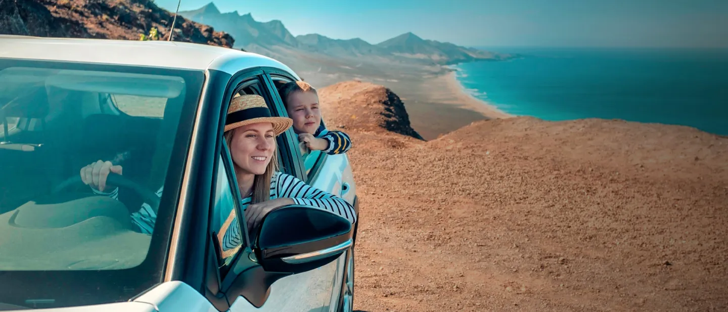 Gente sonriendo en un carro por la costa