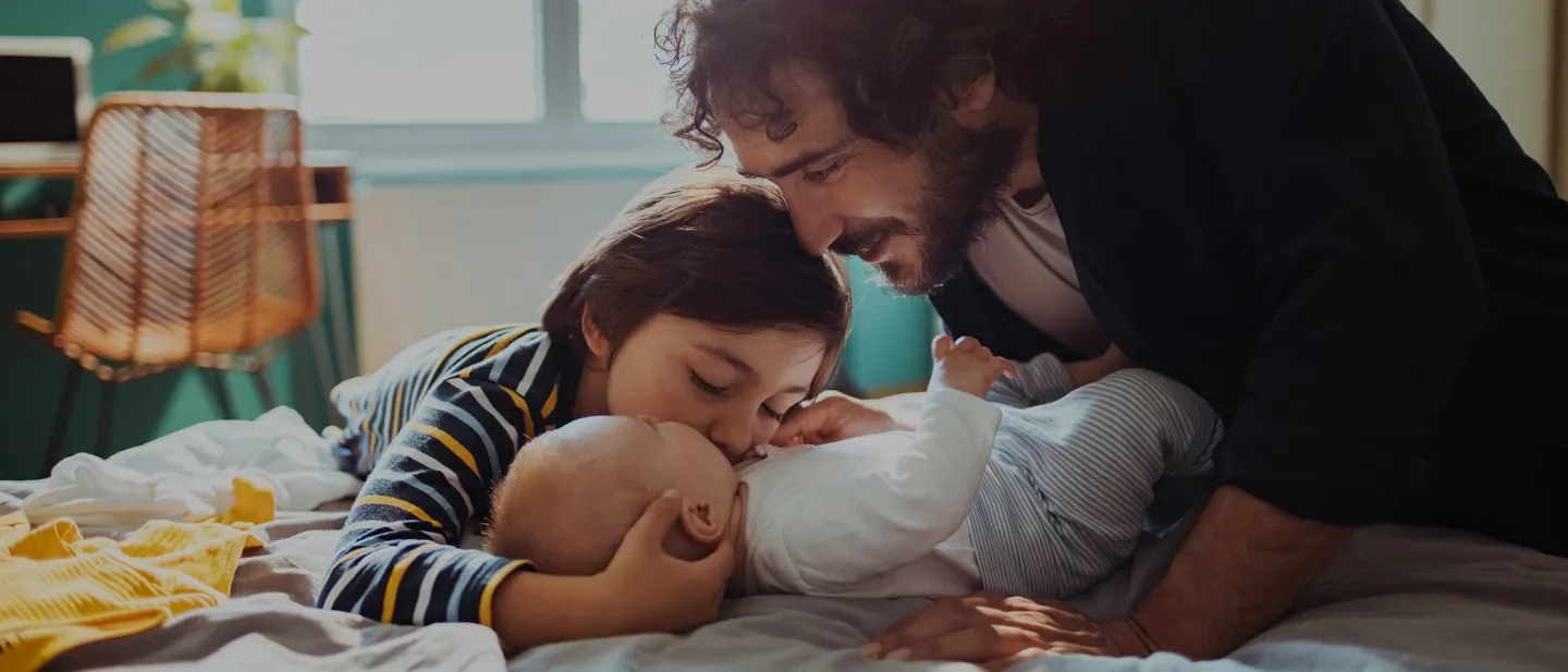 Papá e hijo muy felices con un bebé, gracias a los servicios familiares de Diners Club