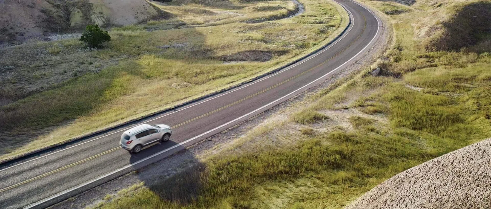 Tarjeta corporativa Gas Club Assist: Un auto circulando por una carretera rodeado de un paisaje de montañas