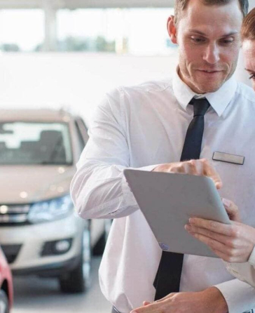 Financiamiento vehicular Diners Club: Personas mirando una tablet junto a un carro