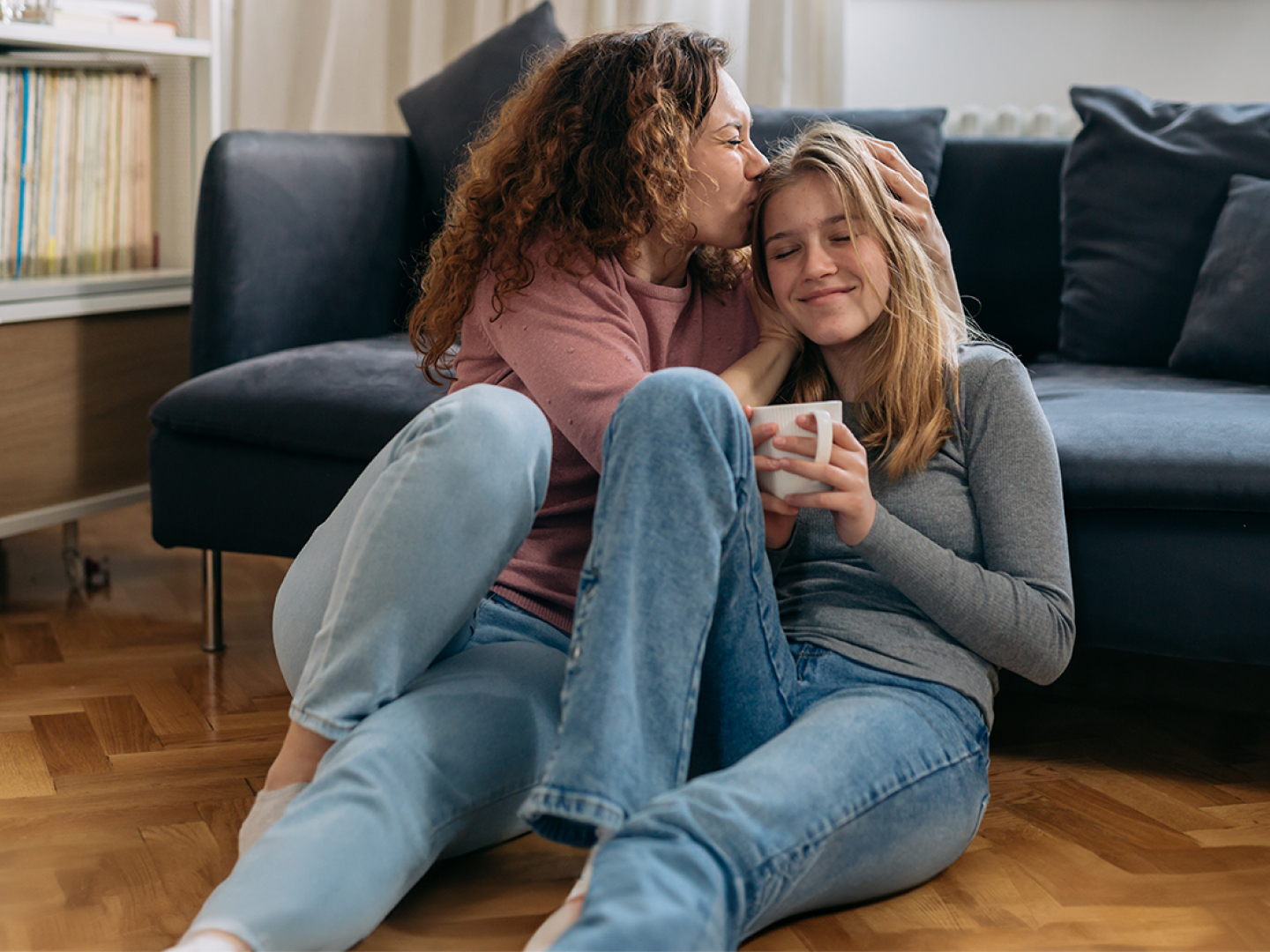 Madre junto a su hija sonriendo y compartiendo en su sala