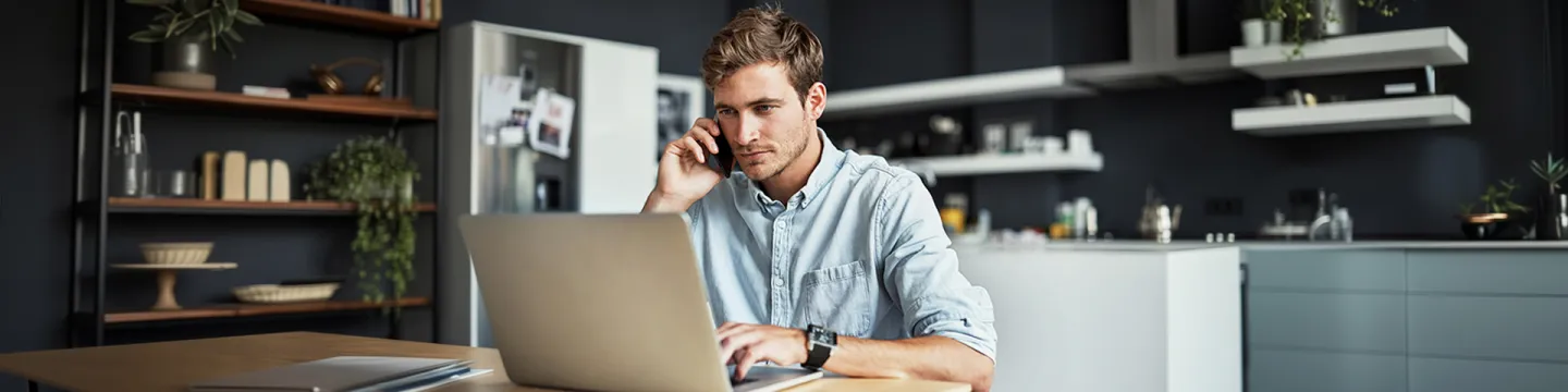Hombre joven con un laptop y un teléfono en la mano